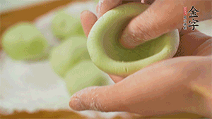 將均分的艾草面團(tuán)搓成圓，挖一個(gè)窩，放入餡心，再搓成圓。