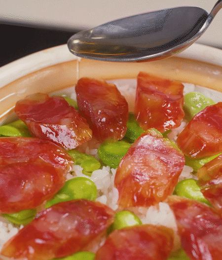 大米出現小孔時開蓋放香腸，往鍋邊淋入少許油，再燜煮8~10分鐘左右。