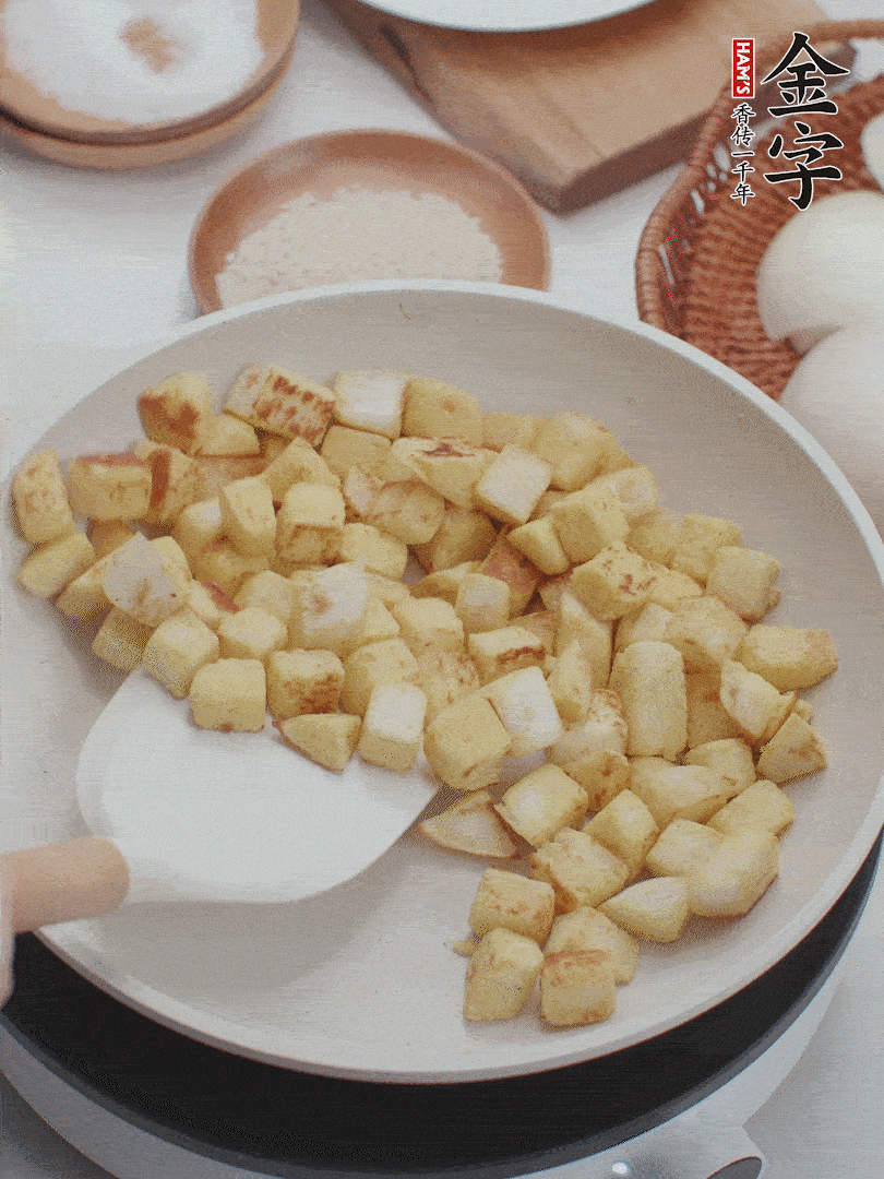 起鍋熱油，倒入饅頭丁，小火煎至蛋液凝固定型再翻面，饅頭丁部煎至金黃時(shí)盛起待用。