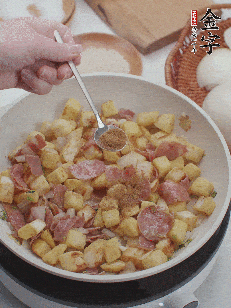 起鍋少油，煸香洋蔥丁、蔥白，加入金字培根火腿翻炒幾下，再加入饅頭丁、1小勺孜然粉、少許鹽翻炒均勻并鋪平。