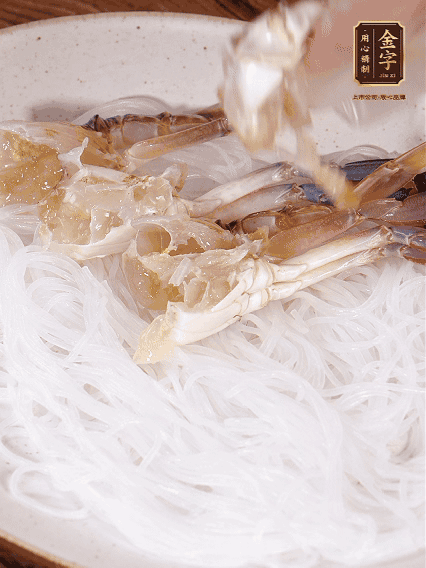 盤底墊上粉絲，擺上梭子蟹、火腿片，撒姜粒，淋上蒸魚豉油、花雕酒調(diào)味腌制15分鐘